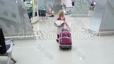 穿着冬装的金发小女孩带着手提箱穿过机场的<strong>候机大厅</strong>。